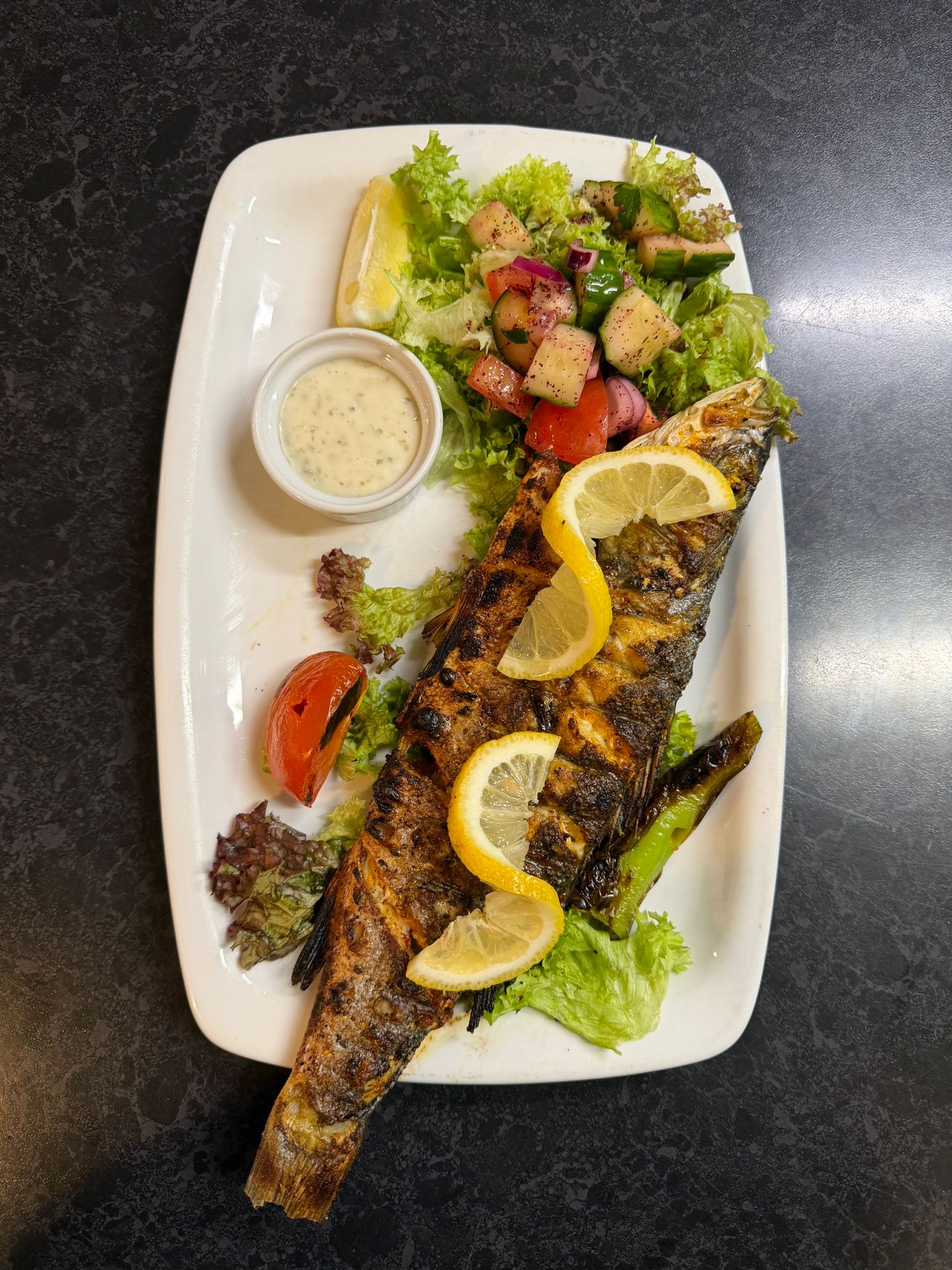 Charcoal grilled sea bass with lemon slices and salad