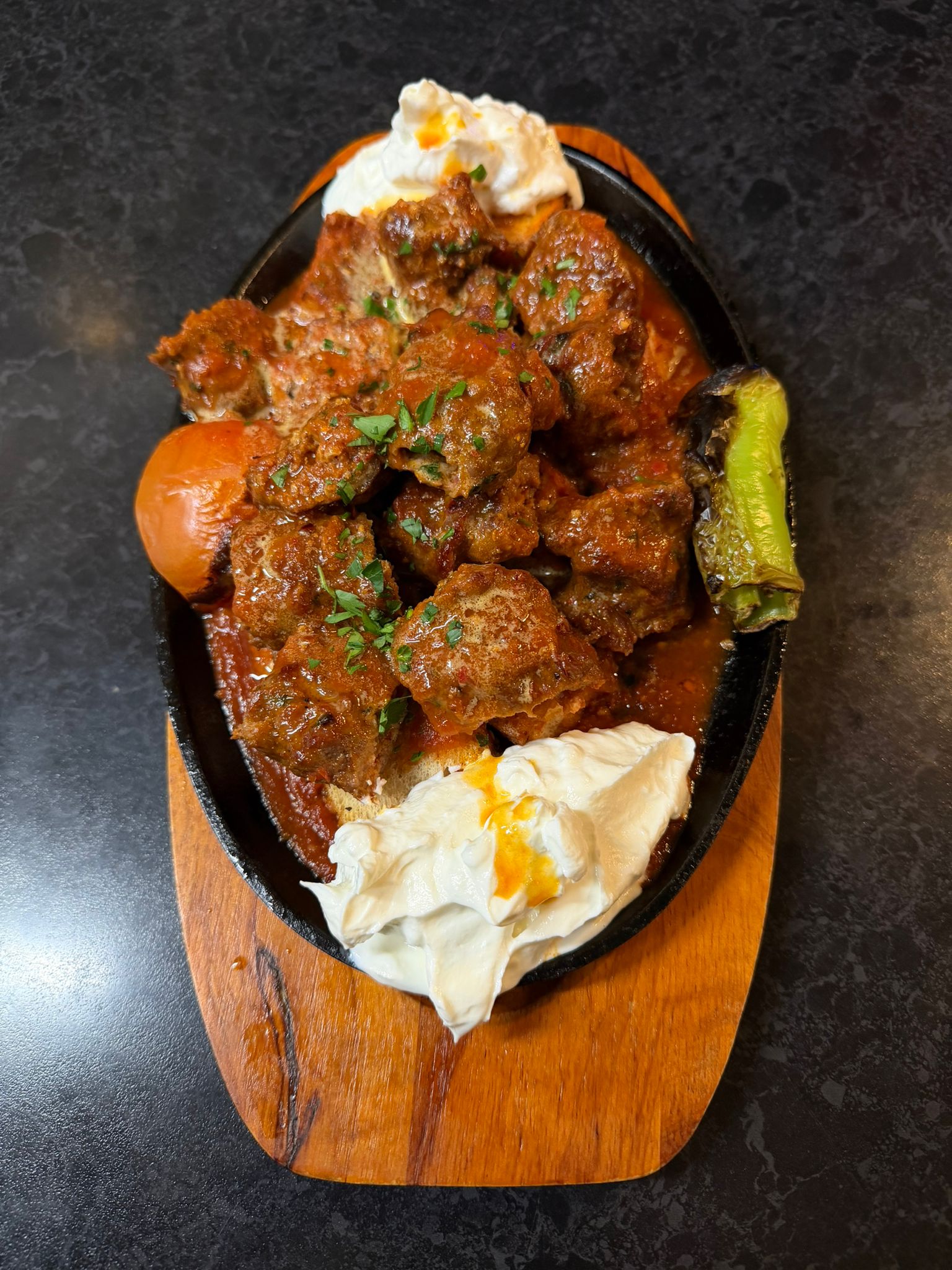 Sizzling lamb stew served on a hot plate with yoghurt