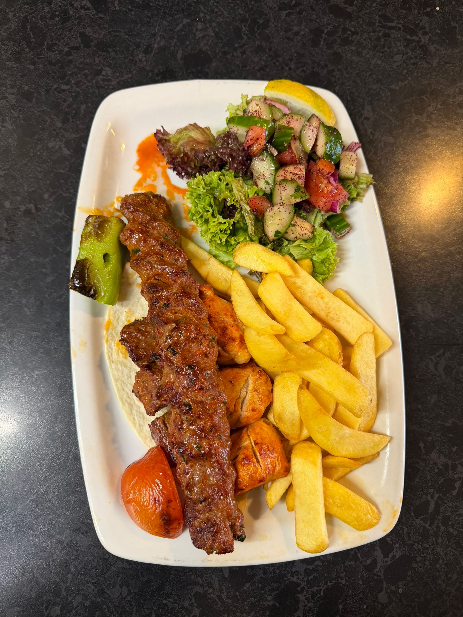 Adana kebab served with golden chips and fresh salad